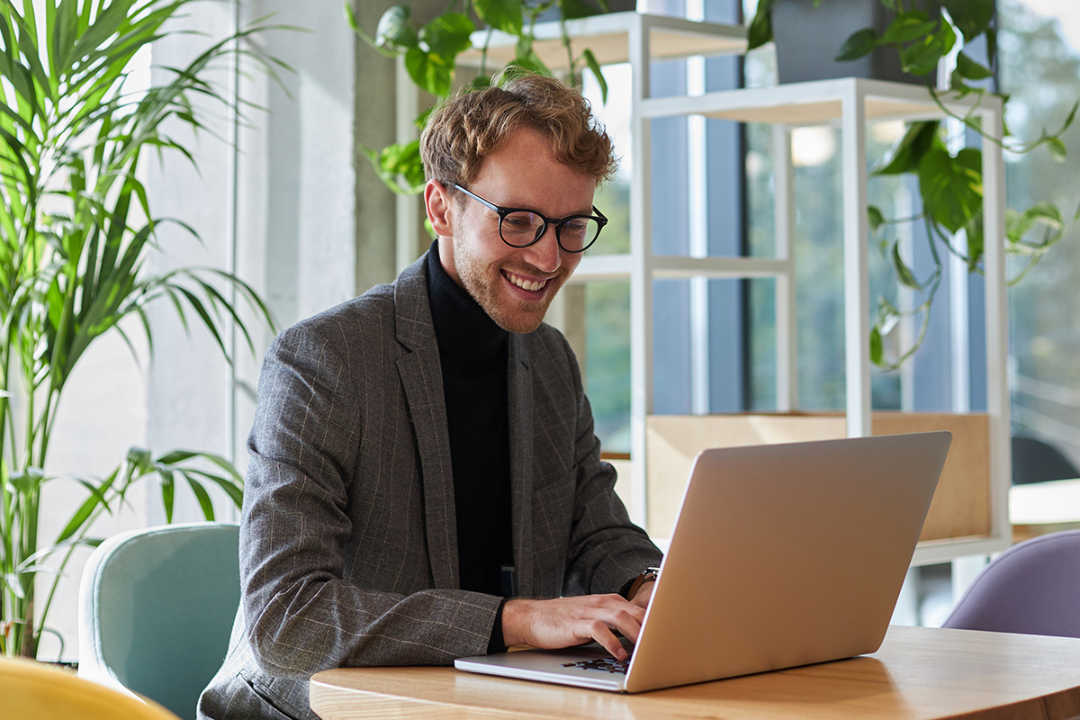jonge zakenman met bril is aan het werk op zijn laptop, maar snel aanpassingen aan de e-learningmodule rond compliance