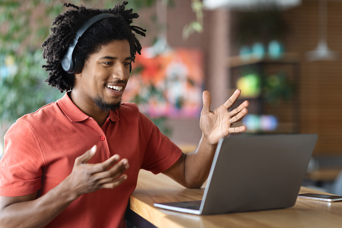 zwarte man aan laptop met hoofdtelefoon, doet digitaal rollenspel uit sales training via e-learning